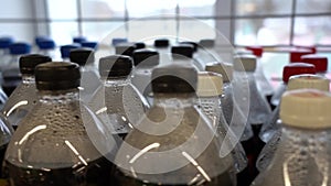 Lots of plastic drinks bottles in the shop by the window. CLOSE-UP. Row of carbonated soft drink bottles