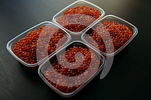 Lots of red caviar in jar. Sea food. Healthy eating. Red salmon caviar. Caviar in bowl over black background. Close-up