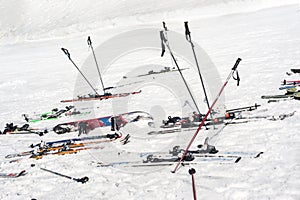 Lots of skis, poles and snowboards, stuck in the snow