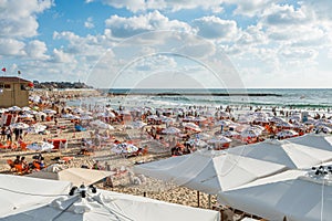 Lots of tourists spending their vacation at beah of Mediterranean sea  and lots of umbrellas at the beach of Tel Aviv, Israel in