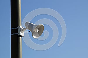 Loud speaker on pole against blue sky