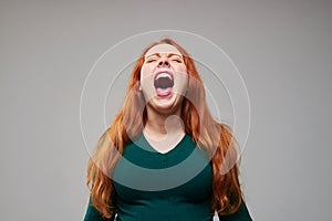Loudly screaming redhead woman expressing negative emot photo