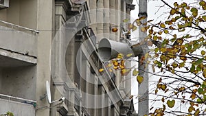 A loudspeaker on a pole in the city against the background of autumn leaves and old city buildings. Announcement of information to