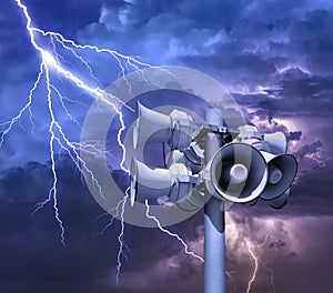 Loudspeakers broadcasting pillar against thunder sky