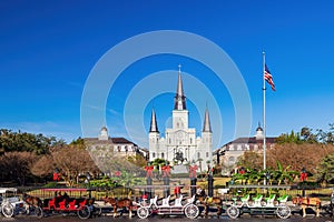 Sunny view of the historical St. Louis Cathedral with many mid centry carriage at French Quarter