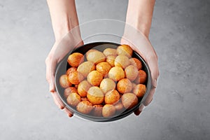 ALoukoumades or luqaimat or lokma in black bowl. Popular Ramadan or Ramazan Food. Iftar or Suhur sweets in female hands photo