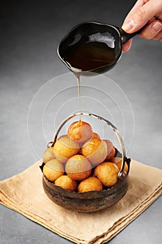 Loukoumades or luqaimat or lokma with syrup in metallic bowl. Popular Ramadan or Ramazan Food. Iftar or Suhur sweets photo