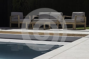Lounge area with wooden seating sofa near to the swimming pool adge in summer time photo