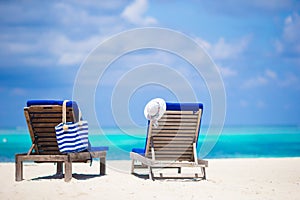 Lounge chairs with bag and hat on tropical beach