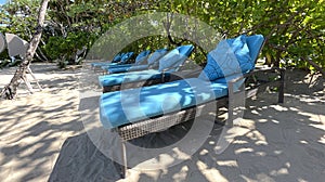 Lounge chairs or beach chairs on white sand beach in hot summer day in luxury tropical hotel