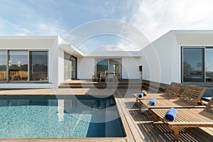 Lounge chairs in modern villa pool