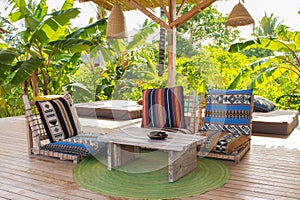 Lounge chairs with pillows and wooden table on the terrace. Cozy patio in hotel resort. Empty tourist villa.