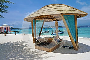 Lounge chairs shaded by a bamboo hut on the beach photo