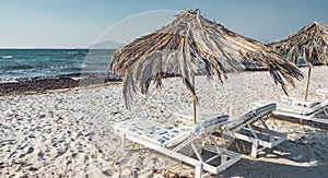 Lounge chairs and straw parasols on the beach by the sea