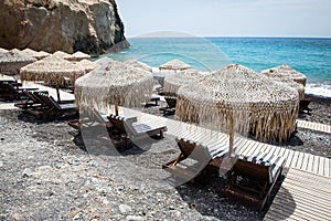 Lounge chairs with umbrellas on the empty White beach in Santorini