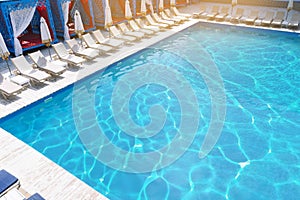 Lounge chairs with umbrellas near swimming pool