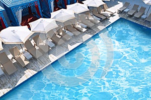 Lounge chairs with umbrellas near swimming pool on day