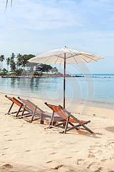 Lounge chairs under umbrella on beach.