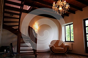 Lounge room with staircase, chair and elegant electrolier