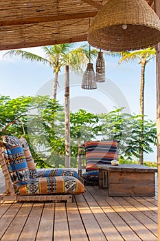 Lounge zone in tropical hotel. Outdoor patio with chairs, pillows, table and palms. Paradise in Zanzibar. Vacation in Africa.