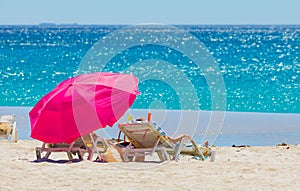 Lounger chairs and parasol umbrellas on sandy beach in Cape Town