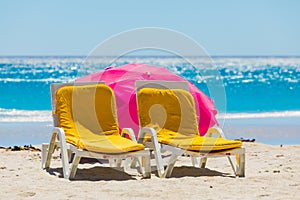 Lounger chairs and parasol umbrellas on sandy beach in Cape Town