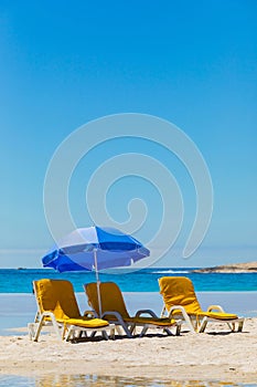 Lounger chairs and parasol umbrellas on sandy beach in Cape Town