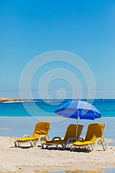 Lounger chairs and parasol umbrellas on sandy beach in Cape Town