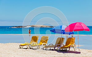 Lounger chairs and parasol umbrellas on sandy beach in Cape Town