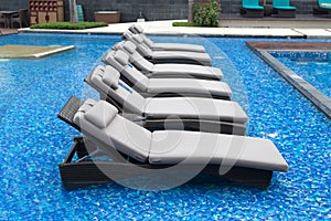 Loungers with towels on a luxurious swimming pool with blue water