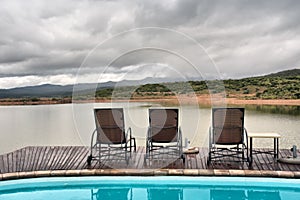 Lounges between swimming pool and lake in mountains