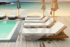 Lounging Sunbeds on Swimming Pool Wooden Deck with Seascape Background