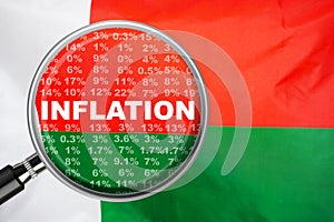 Loupe focused on the word inflation on Madagascar flag background. Inflation, tax, financial concept in Madagascar