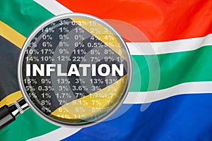 Loupe focused on the word inflation on South Africa flag background. Inflation, tax, financial concept in South Africa