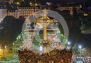 LOURDES, FRANCE - SEPTEMBER 14 2019: Cross in front of the candle procession, every night in Lourdes, France, Europe