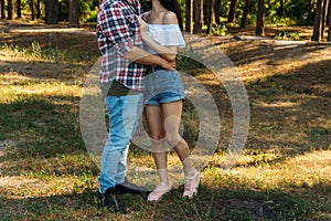 embrace.Love and affection between a young couple at the park. a guy in a plaid plane and jeans, a girl in shorts and a white jack