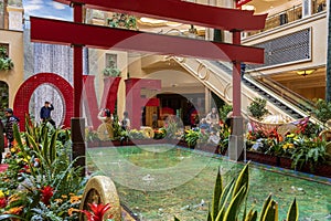 The Love Art Sculpture in the waterfall atrium at The Venetian Resort and Hotel with lush green trees and plants, colorful flowers