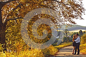 Love among the autumn trees - coule hugs on the path in the park