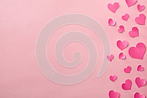 Love background with fuxia heart cutouts of various sizes on a pink background