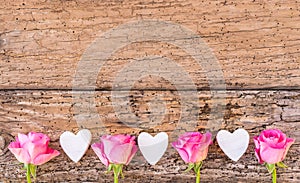 Love hearts and pink roses flowers border on rustic wood, love background for Wedding or Valentines Day