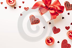 Love background: Valentines day red hearts, romantic gift box, candle on white table. Romantic message template with copy space.