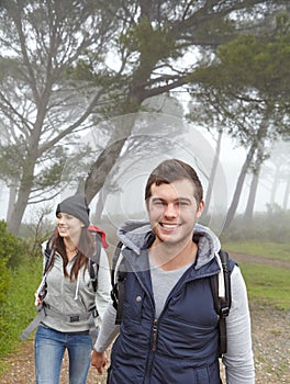 They love being out in nature. a handsome young man hiking through a forest with his girlfriend.
