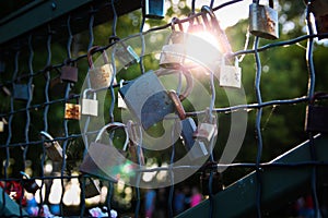 Love bond symbol. Locks on metallic fence, with sun behind them.