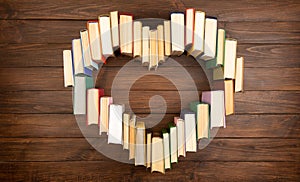 Love of books reading. Stack of books in the colored cover lay on the table in the shape of a heart. Library, education. Empty