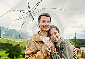 Love can make a rainy day seem sunny. a loving couple standing outside with an umbrella.