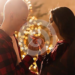 Love, christmas, couple, proposal and people concept - happy man giving diamond engagement ring to woman at home