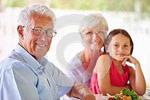 We love when she comes to visit. Portrait of a little girl having lunch with her grandparents.