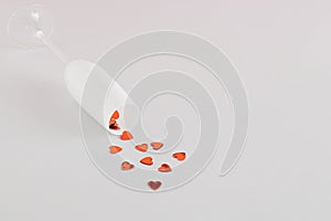 Love composition with red hearts spilled from champagne glass on a gray background. Minimal love or Valentine`s Day concept