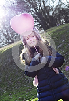 Love concept: child holding a heart-shaped baloon on a stick.
