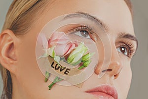 Love concept. Closeup woman face with roses flowers and love inscription